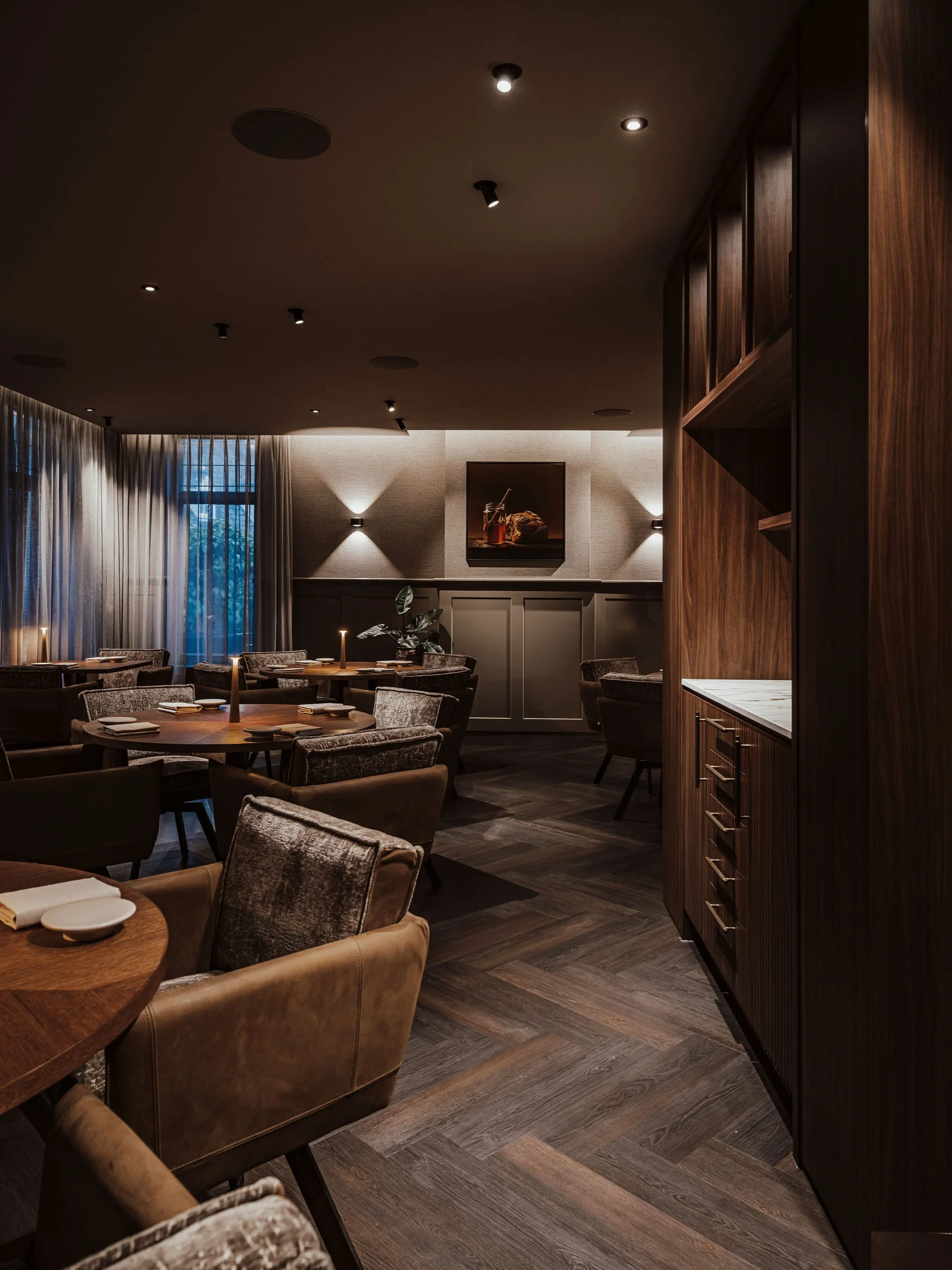 Sfeervol restaurantinterieur met warme verlichting, leren stoelen en houten tafels