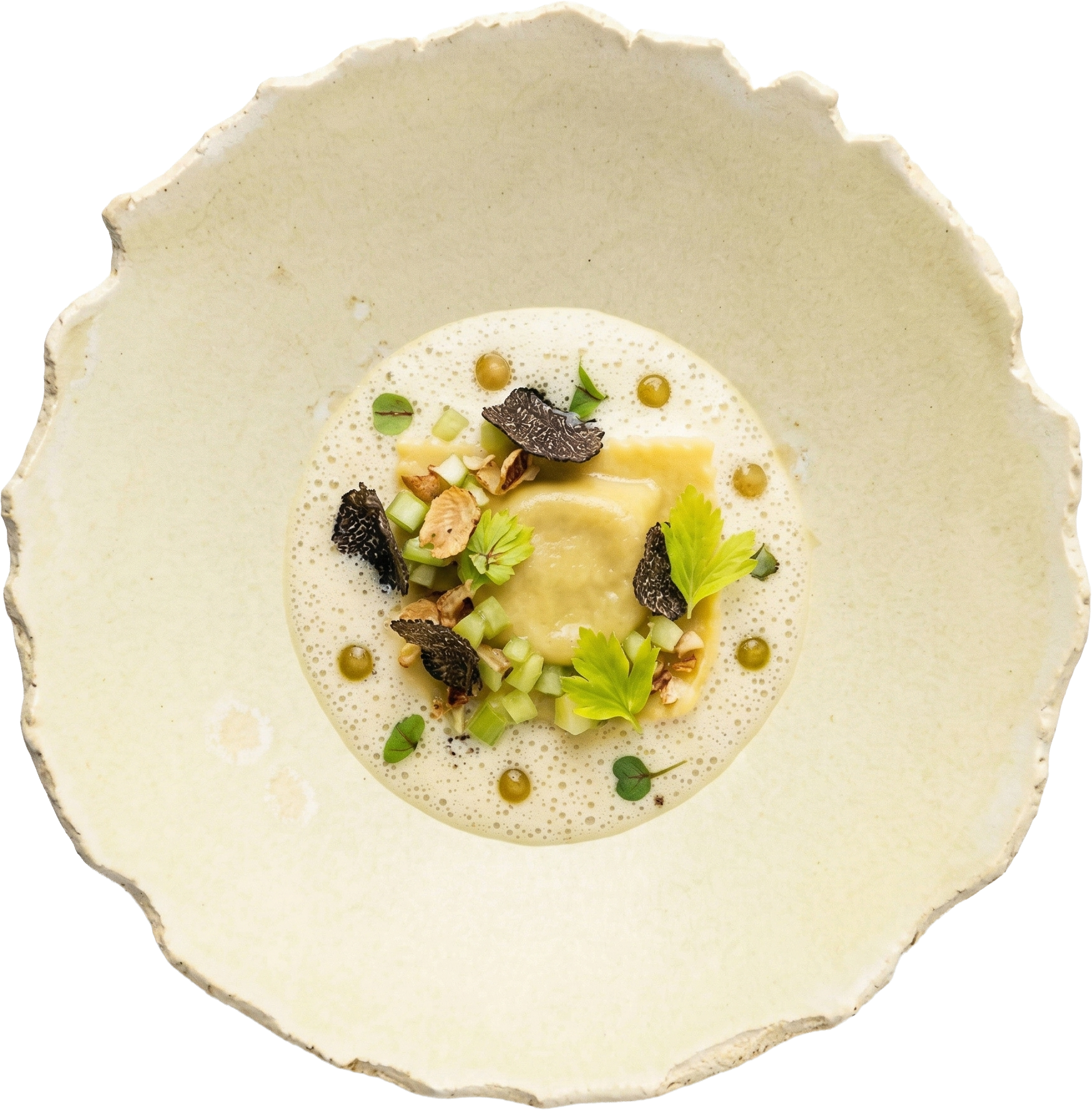 Ravioli met romige saus, zwarte truffel, selderij en walnoot op een ambachtelijk bord