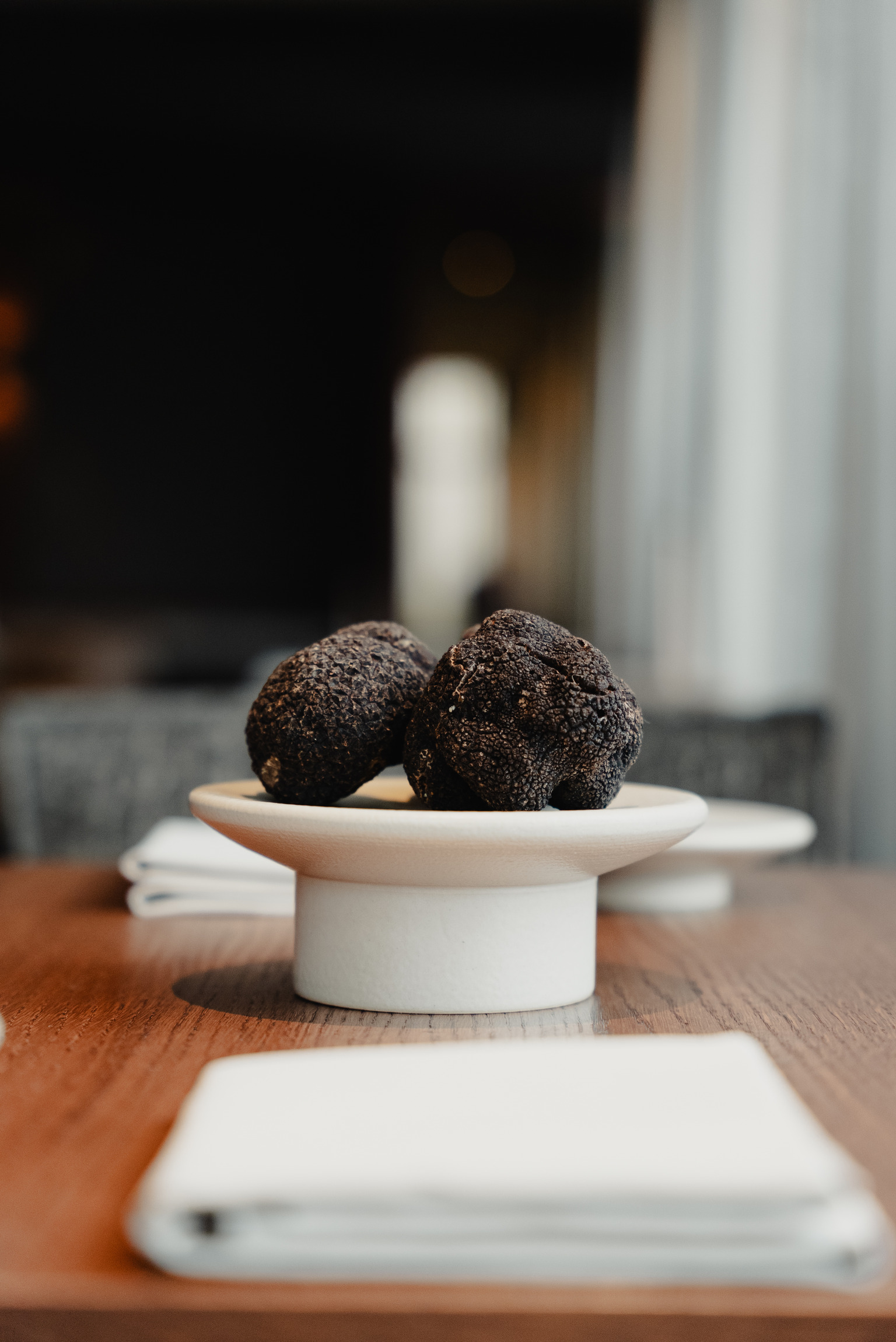 Twee verse zwarte truffels op een wit keramisch schaaltje op een houten tafel